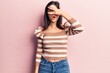 © Krakenimages.com - Young beautiful girl wearing casual striped t shirt peeking in shock covering face and eyes with hand, looking through fingers afraid