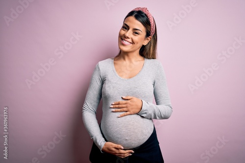 Fotografía Young beautiful brunette woman pregnant expecting baby over isolated pink background with a happy and cool smile on face