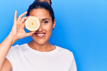 Sticker - Young beautiful brunette woman holding slice of lemon looking positive and happy standing and smiling with a confident smile showing teeth