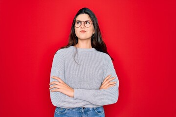 Canvas Print - Young beautiful brunette woman wearing casual sweater over red background smiling looking to the side and staring away thinking.