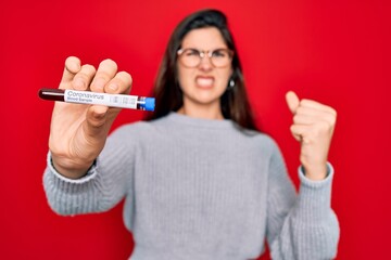 Canvas Print - Young beautiful girl wearing glasses holding laboratory blood sample of coronavirus disease annoyed and frustrated shouting with anger, crazy and yelling with raised hand, anger concept