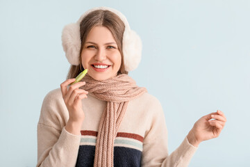 Poster - Beautiful young woman with lip balm on light background