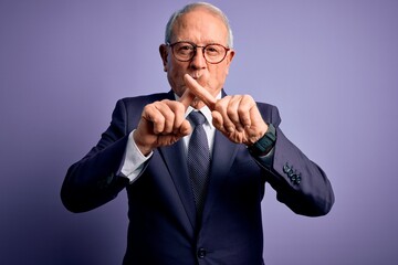 Canvas Print - Grey haired senior business man wearing glasses and elegant suit and tie over purple background Rejection expression crossing fingers doing negative sign