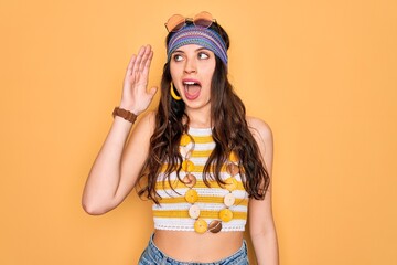 Wall Mural - Young beautiful hippie woman with blue eyes wearing accesories and sunnglasses shouting and screaming loud to side with hand on mouth. Communication concept.