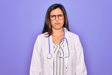 Sticker - Professional doctor woman wearing stethoscope and medical coat over purple background depressed and worry for distress, crying angry and afraid. Sad expression.