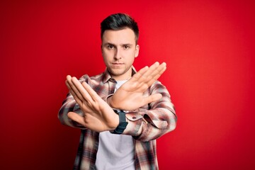 Wall Mural - Young handsome caucasian man wearing casual modern shirt over red isolated background Rejection expression crossing arms and palms doing negative sign, angry face