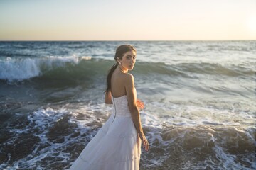 Poster - Brunette caucasian bride posing in the water of the sea in a white wedding dress