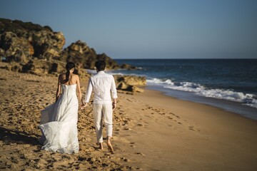 Poster - Bride and the groom walking at the sandy beach