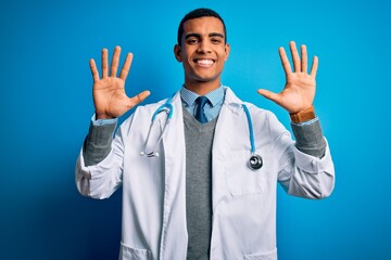Wall Mural - Handsome african american doctor man wearing coat and stethoscope over blue background showing and pointing up with fingers number ten while smiling confident and happy.