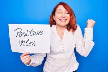 Sticker - Young redhead woman asking for optimist attitude holding paper with positive vibes message screaming proud, celebrating victory and success very excited with raised arm