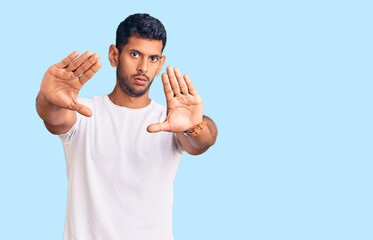 Sticker - Young latin man wearing casual clothes doing frame using hands palms and fingers, camera perspective