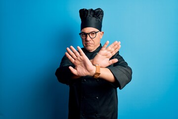 Wall Mural - Middle age handsome grey-haired chef man wearing cooker uniform and hat Rejection expression crossing arms doing negative sign, angry face