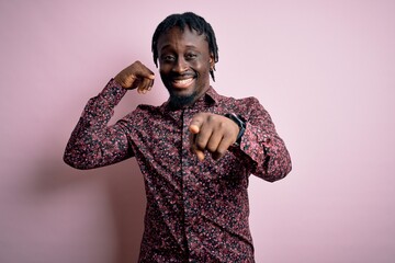 Poster - Young handsome african american man wearing casual shirt standing over pink background smiling doing talking on the telephone gesture and pointing to you. Call me.