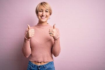 Canvas Print - Young blonde woman with short hair wearing casual turtleneck sweater over pink background success sign doing positive gesture with hand, thumbs up smiling and happy. Cheerful expression and winner