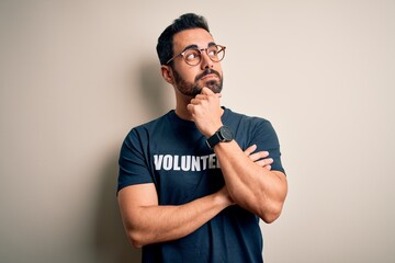 Sticker - Handsome man with beard wearing t-shirt with volunteer message over white background with hand on chin thinking about question, pensive expression. Smiling with thoughtful face. Doubt concept.