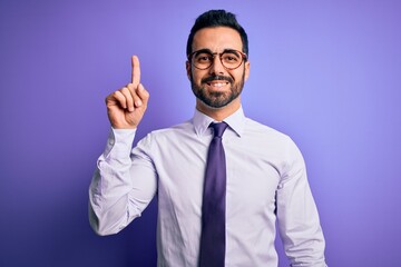 Poster - Handsome businessman with beard wearing casual tie and glasses over purple background pointing finger up with successful idea. Exited and happy. Number one.