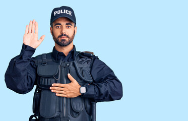 Canvas Print - Young hispanic man wearing police uniform swearing with hand on chest and open palm, making a loyalty promise oath