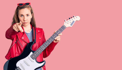 Poster - Young beautiful blonde woman playing electric guitar pointing with finger to the camera and to you, confident gesture looking serious