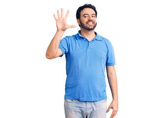 Young hispanic man wearing casual clothes showing and pointing up with fingers number five while smiling confident and happy.