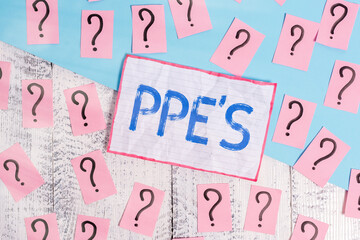 Poster - Handwriting text Ppe s is. Conceptual photo Specialized equipment for protection against health and safety hazard Scribbled and crumbling papers with thick cardboard above wooden table