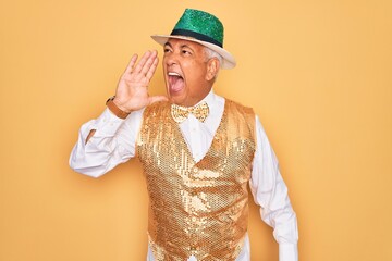 Poster - Middle age senior grey-haired man wearing Brazilian carnival custome over yellow background shouting and screaming loud to side with hand on mouth. Communication concept.