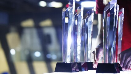 on award ceremony, young woman in red dress placing amazing crystal trophies on shelf preparing priz