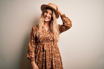 Sticker - Young beautiful blonde woman wearing summer dress and hat over isolated white background confuse and wonder about question. Uncertain with doubt, thinking with hand on head. Pensive concept.