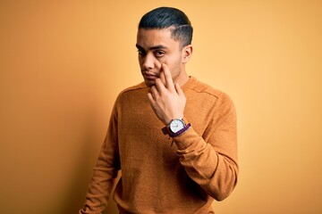 Wall Mural - Young brazilian man wearing casual sweater standing over isolated yellow background Pointing to the eye watching you gesture, suspicious expression