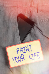 Handwriting text writing Paint Your Life. Conceptual photo Taking control and create your future to achieve goals Smartphone device inside formal work trousers front pocket near note paper