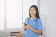 © Have a nice day  - Asian doctor female stethoscope looked at phone in ER hospital ,OR,operating theatre,surgical room,healthcare and medical concept,stethoscope on neck ,Medical technology   Electronic medical record