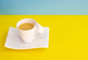 Wall Mural - Closeup shot of a cup of coffee on yellow and green background