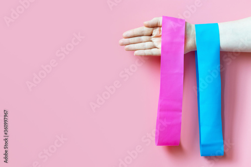 Fotomural The girl holds two fitness gums, espander on pink background, copy space