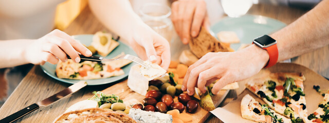 Table full of tasty and delicious food close-up. Pizza, cheeze, olives eating with hands. Wide screen, panoramic