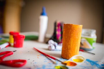 Sticker - Closeup horizontal shot of yellow cardboard tube on a background of painting materials for children