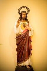 Wall Mural - Vertical shot of a statue of Jesus Christ in a red robe on a yellow background