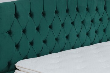 Canvas Print - Closeup shot of a bed with green fabric headboard and white mattress