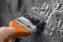 Hand Of Worker Use Brush For Black Color Paint Concrete On Wall.