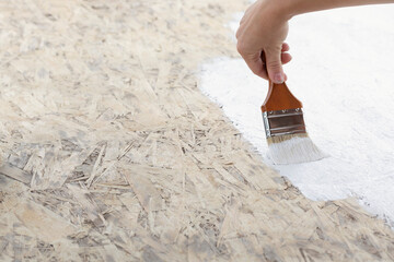 close up of brush with white paint on wooden surface