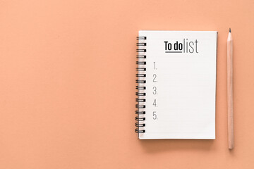 notebook and pencil with to do list words on pastel color background.