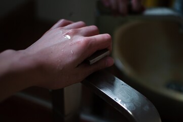 Wall Mural - Woman's wet hands on the metal faucet