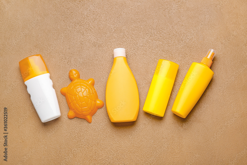 Sunscreen cream with beach sand toy on color background
