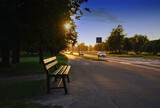 Fototapeta Do pokoju - bench near city road at  sunset