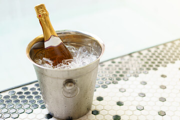 Champagne bottle in ice bucket and two glasses near bubble pool