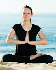 Wall Mural - Girl in black T-shirt is sitting and practicing yoga