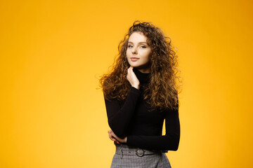 Wall Mural - Pretty girl with curly hair on yellow background