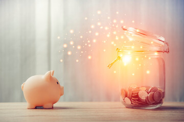 piggy bank and money bottle on a wooden table with blurred blue background