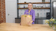 Young woman unpacking bags with groceries in kitchen