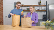 Couple Returning Home From Shopping Trip Carrying Groceries In Paper Bags