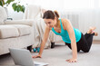 © Admiral - Online home fitness. Slim girl doing workout routine on floor and watching laptop at home. Copy space