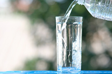 Poster - Glass of water on wood table background and pouring drinking water